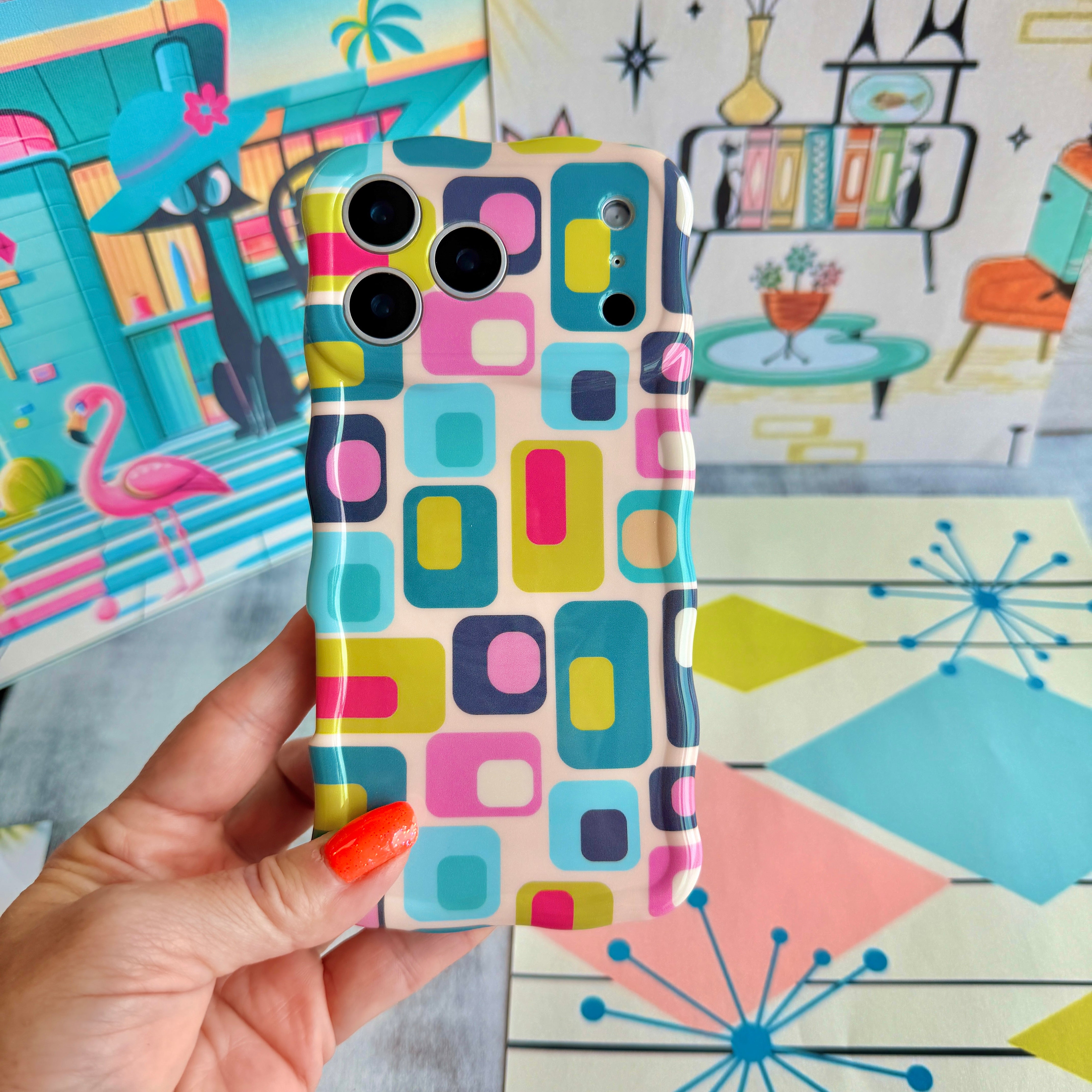 Hand holding the Mod Mood Wavy Luxe MagSafe iPhone case with teal, lime, pink and navy rounded squares on a retro atomic starburst backdrop