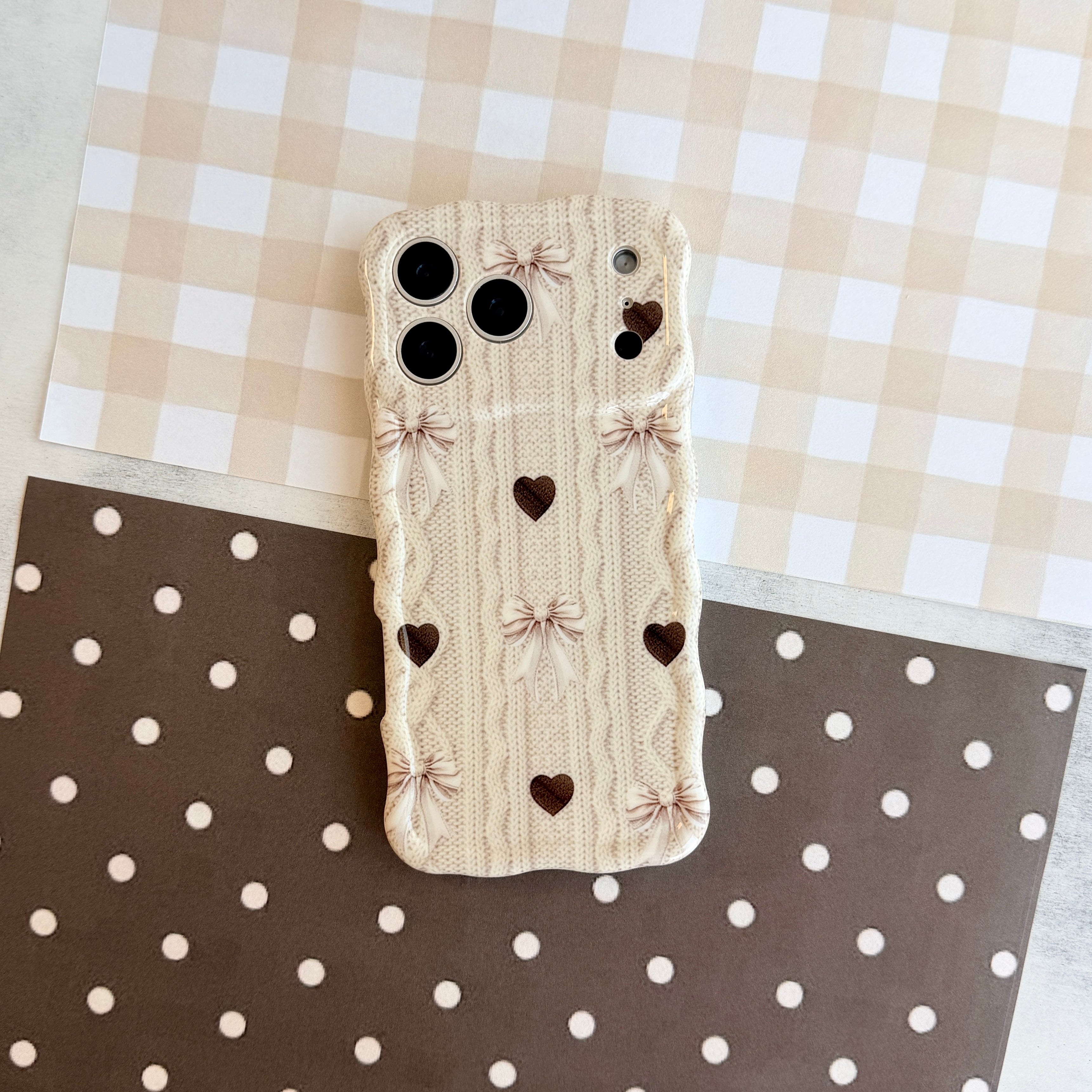 Sweater Weather Sweetheart Wavy Luxe MagSafe iPhone case shown on iPhone with the signature wavy edge and cozy knit, bow, and heart print design.