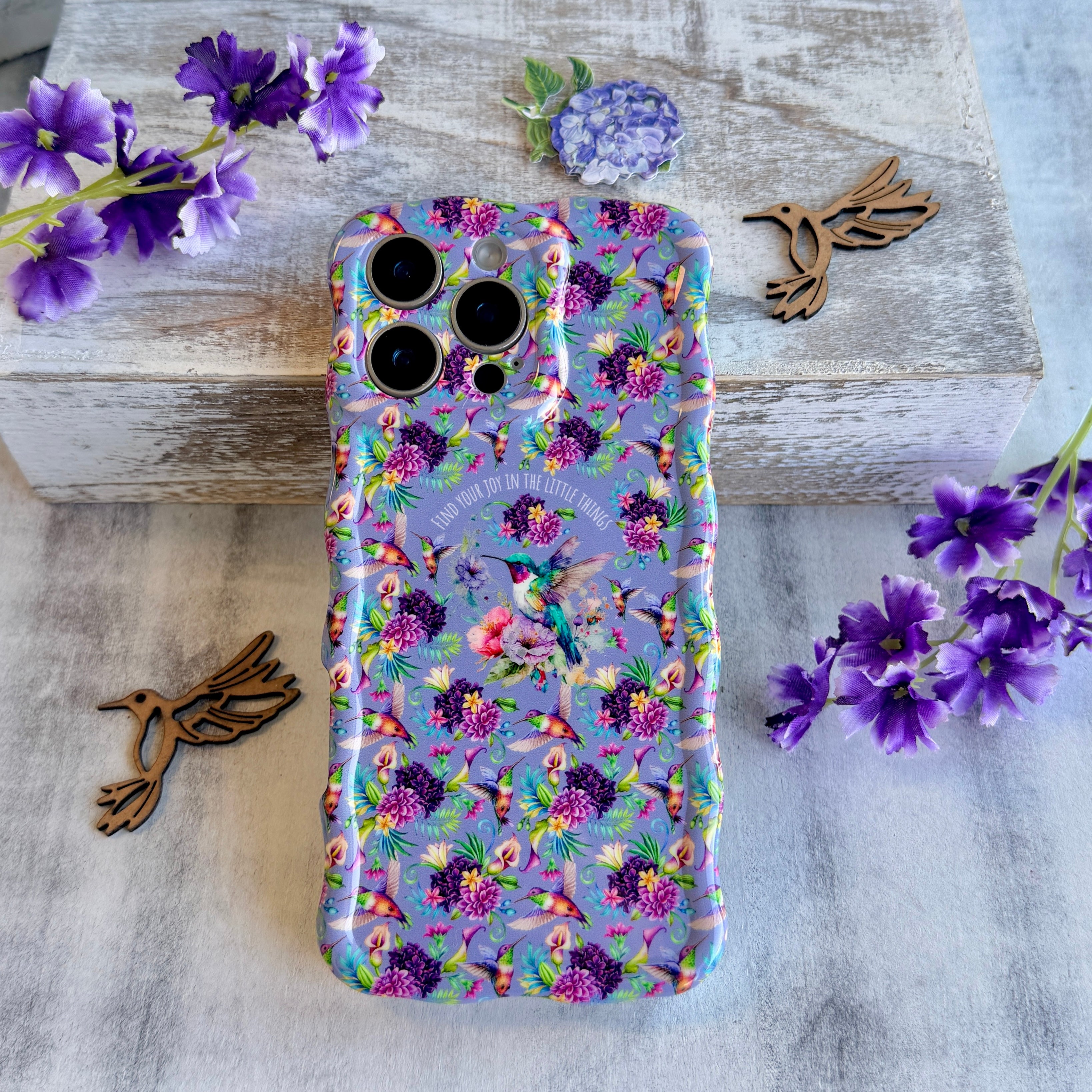 Lavender wavy iPhone case featuring colorful hummingbirds, purple flowers, and the quote Find Your Joy In The Little Things.