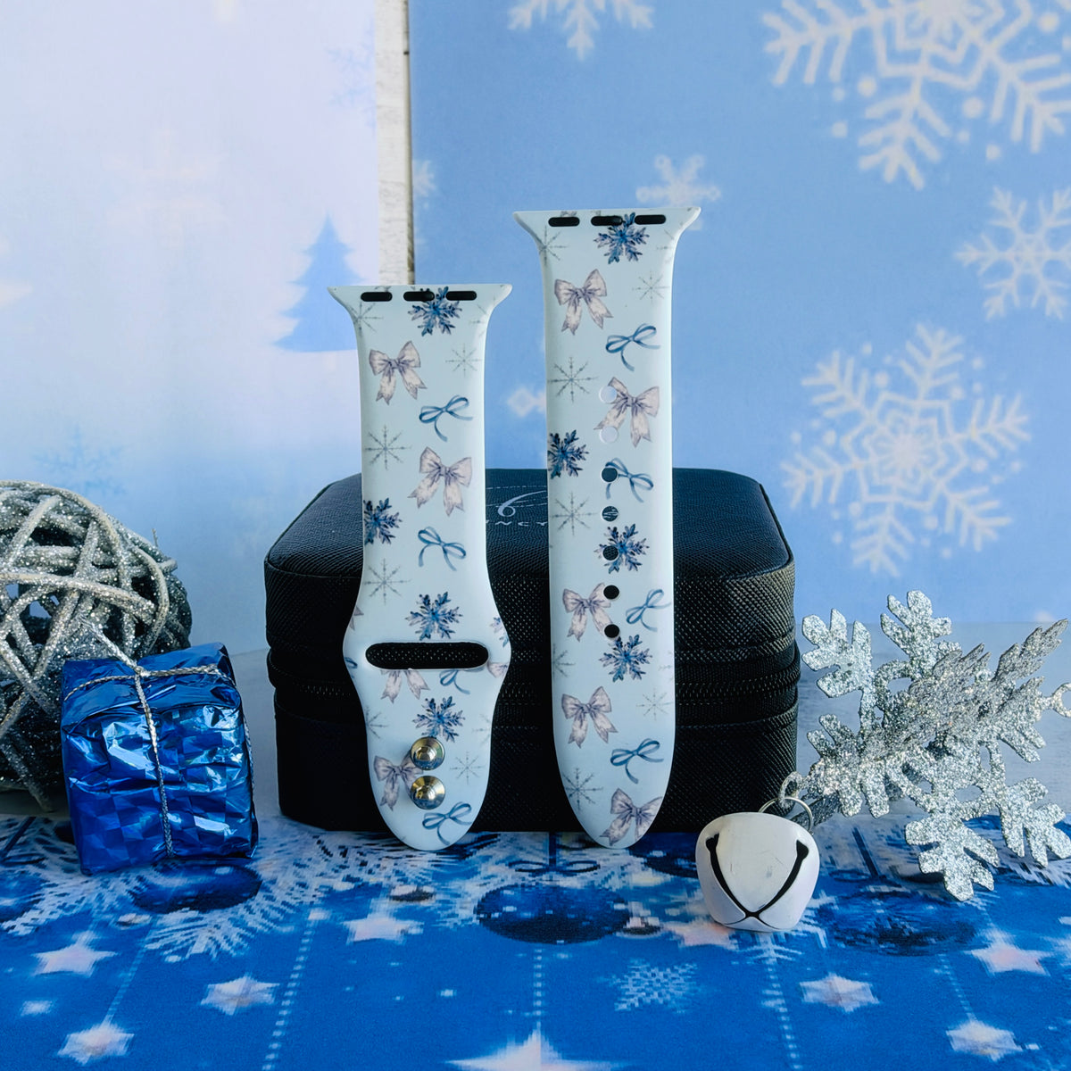 Both Snow Pretty In Blue Apple Watch band straps on a black jewelry box with a metallic blue gift and a silver glitter ball