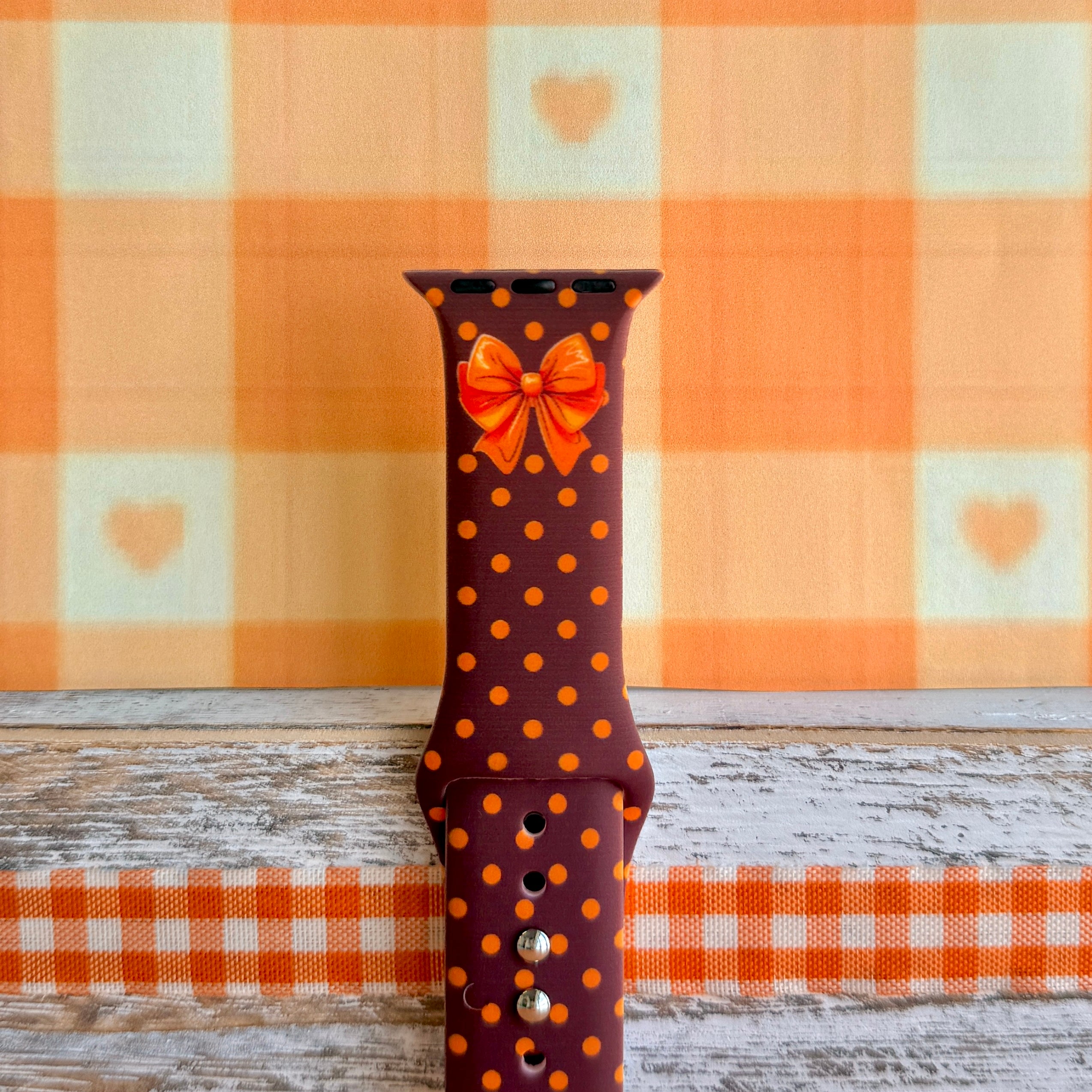 Close-up of the Spotted Looking Cute Apple Watch band showing the crisp orange and red bow artwork, pumpkin-orange dots, and the adjustment pin holes.