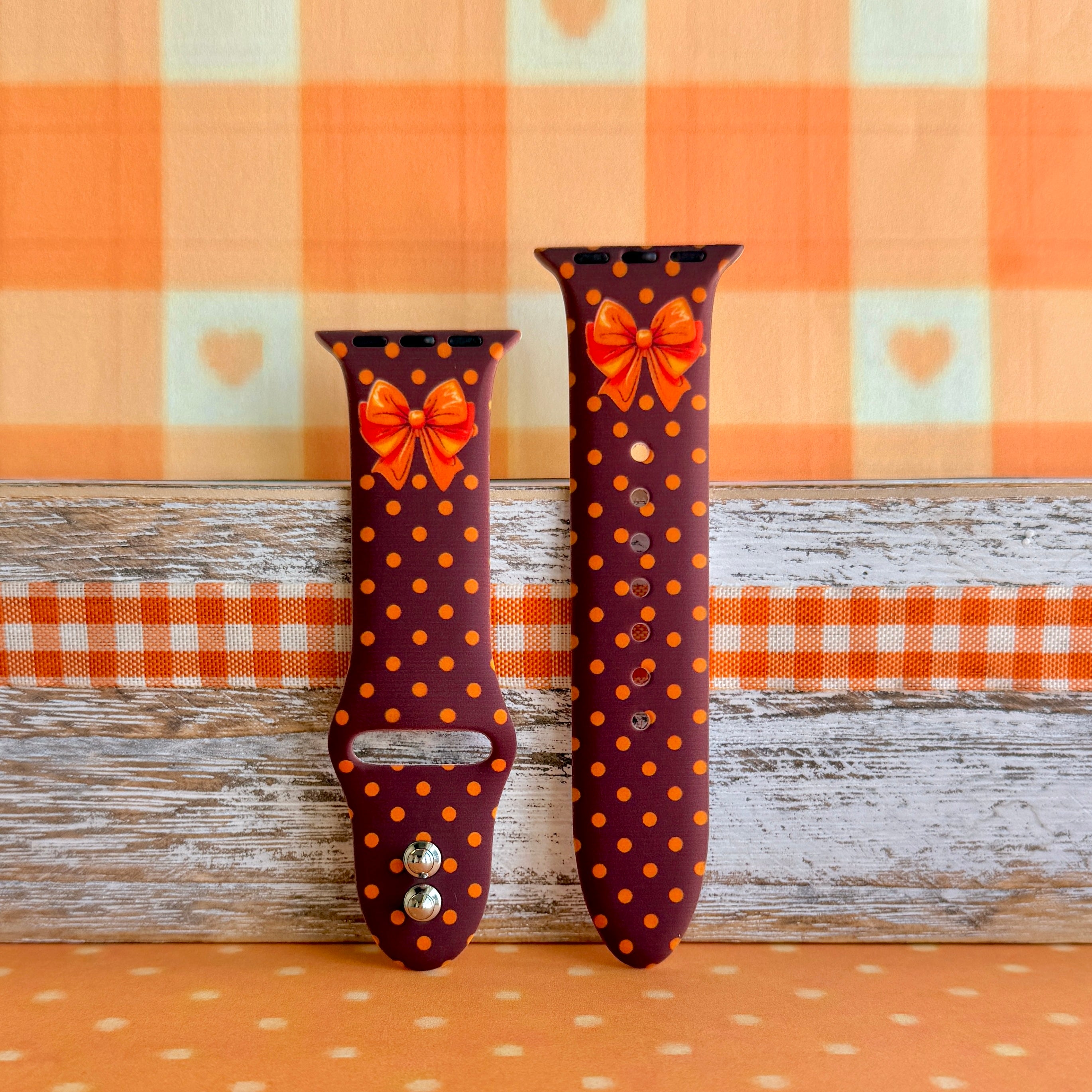 Spotted Looking Cute Apple Watch band with both strap halves side by side on weathered wood and orange gingham, showing the full brown and orange polka dot print.