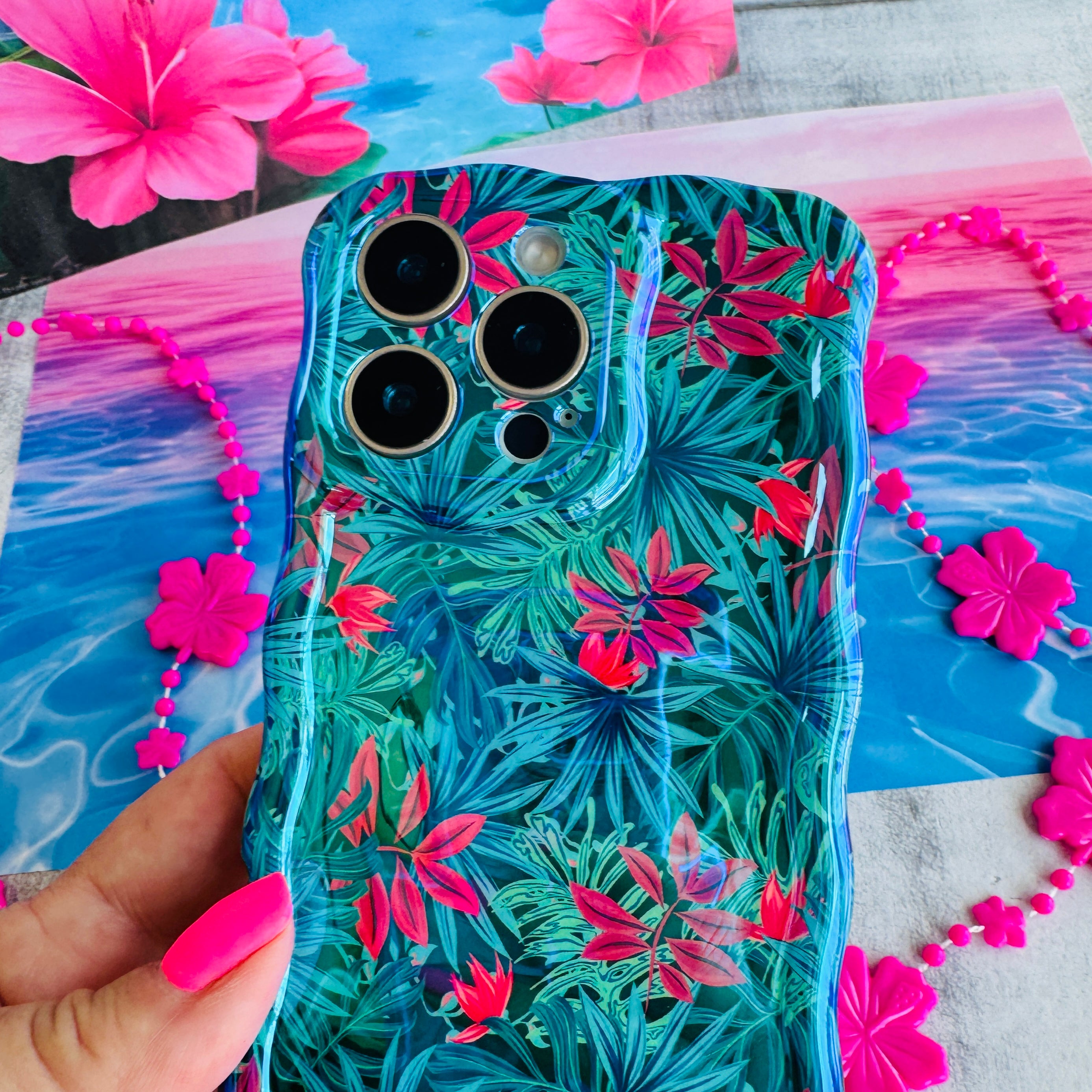 Phone case with floral design held by a hand against a colorful background
