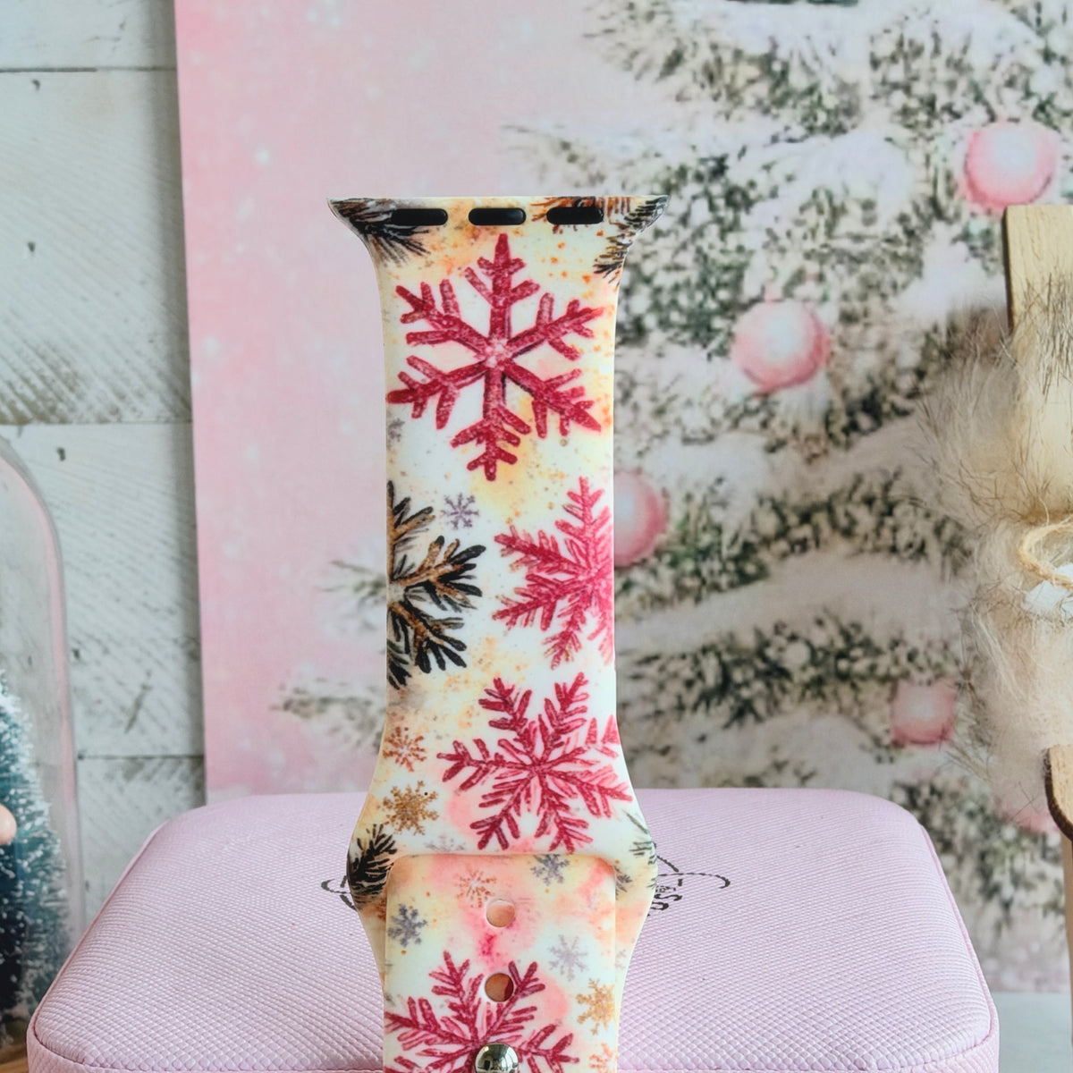Close-up of a single Champagne Snowfall Apple Watch band strap, pink snowflake print
