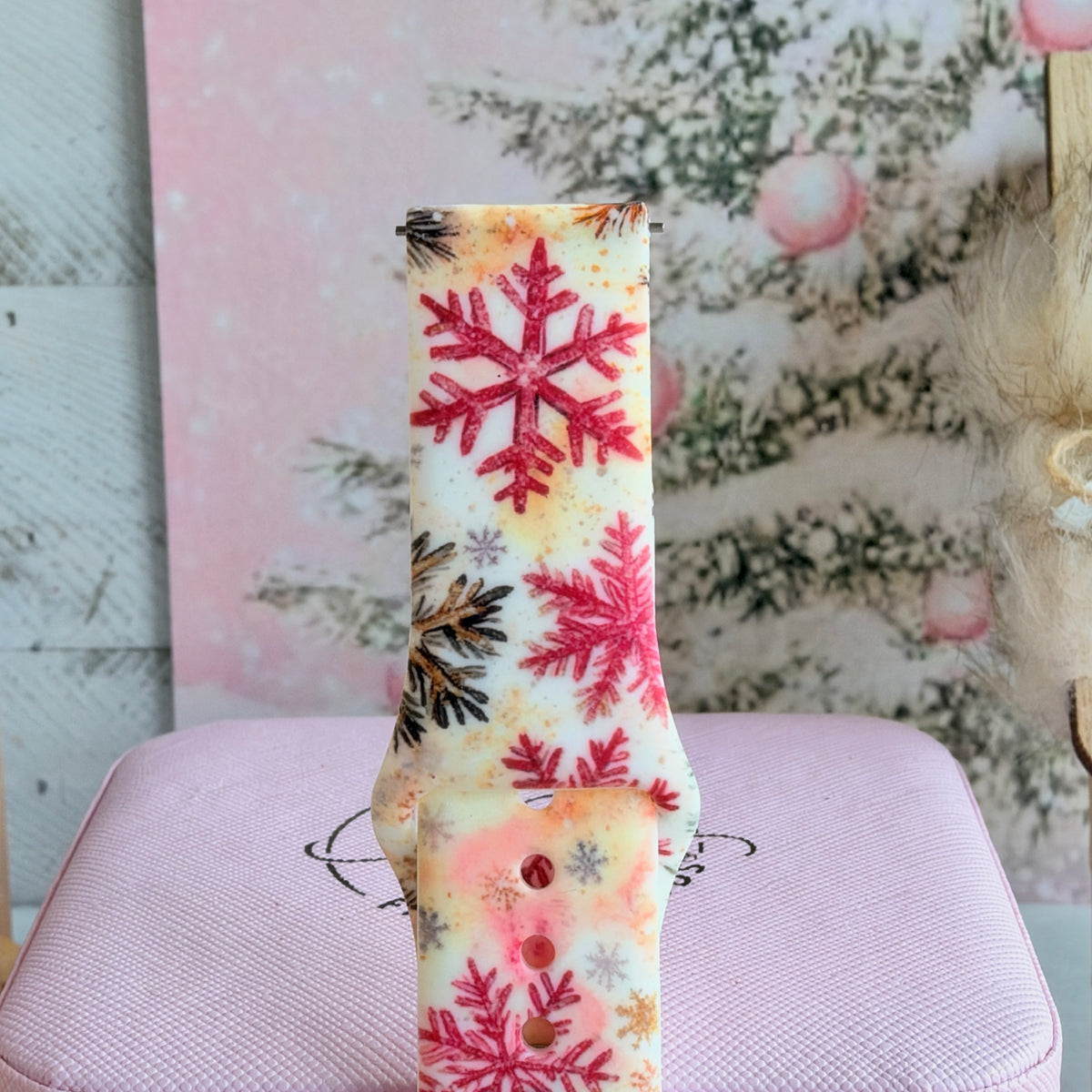 Close-up of a single Champagne Snowfall Samsung watch band strap, pink snowflake print on a peach watercolor ground