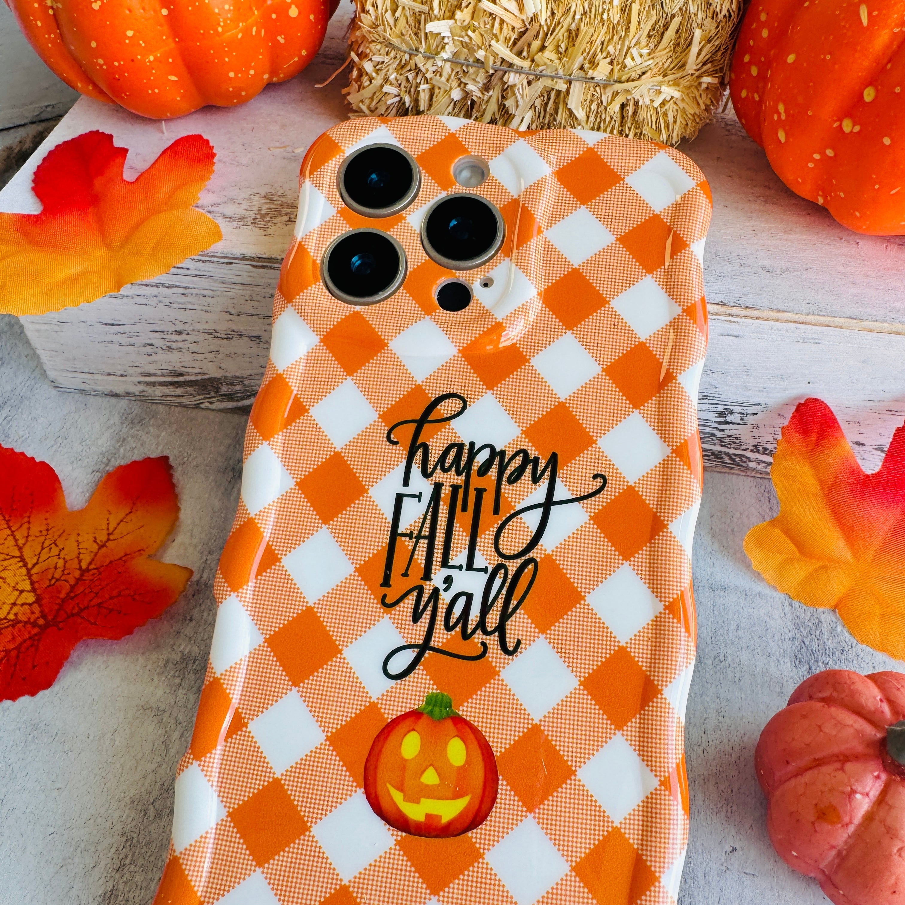Happy Fall Y'all Wavy Luxe MagSafe iPhone case in orange-and-white gingham with a jack-o'-lantern accent, styled with fall decor