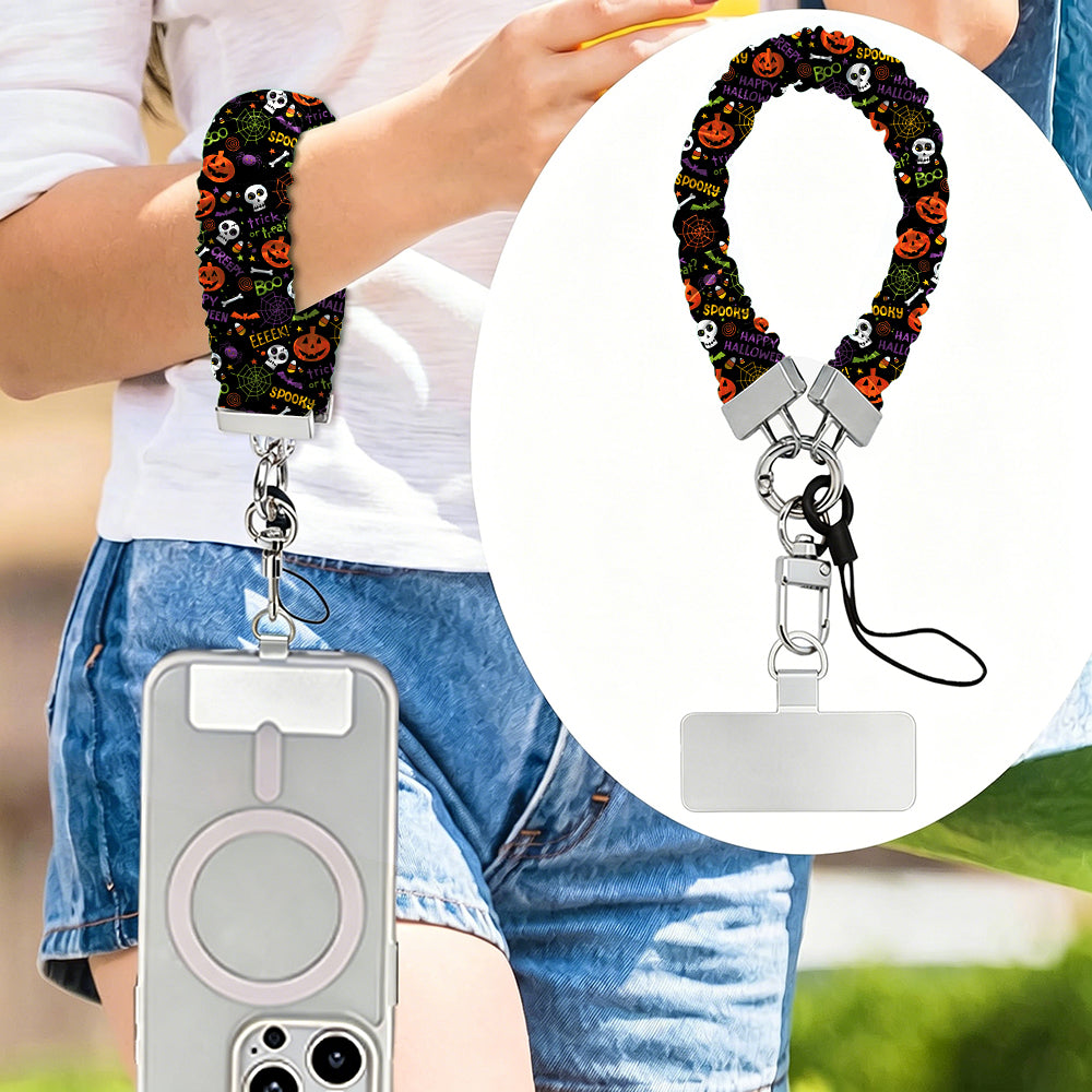 Spooky scrunchie phone wrist strap worn on the wrist and clipped at the hip, with a close-up of the black pumpkin and skull print