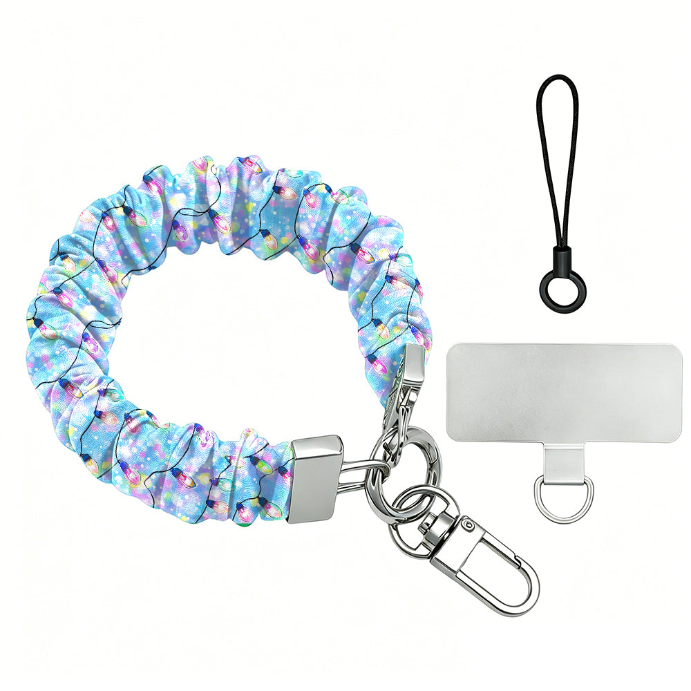 Twinkle All The Way scrunchie phone wrist strap laid flat with silver clasp and phone tab, pastel Christmas lights on blue