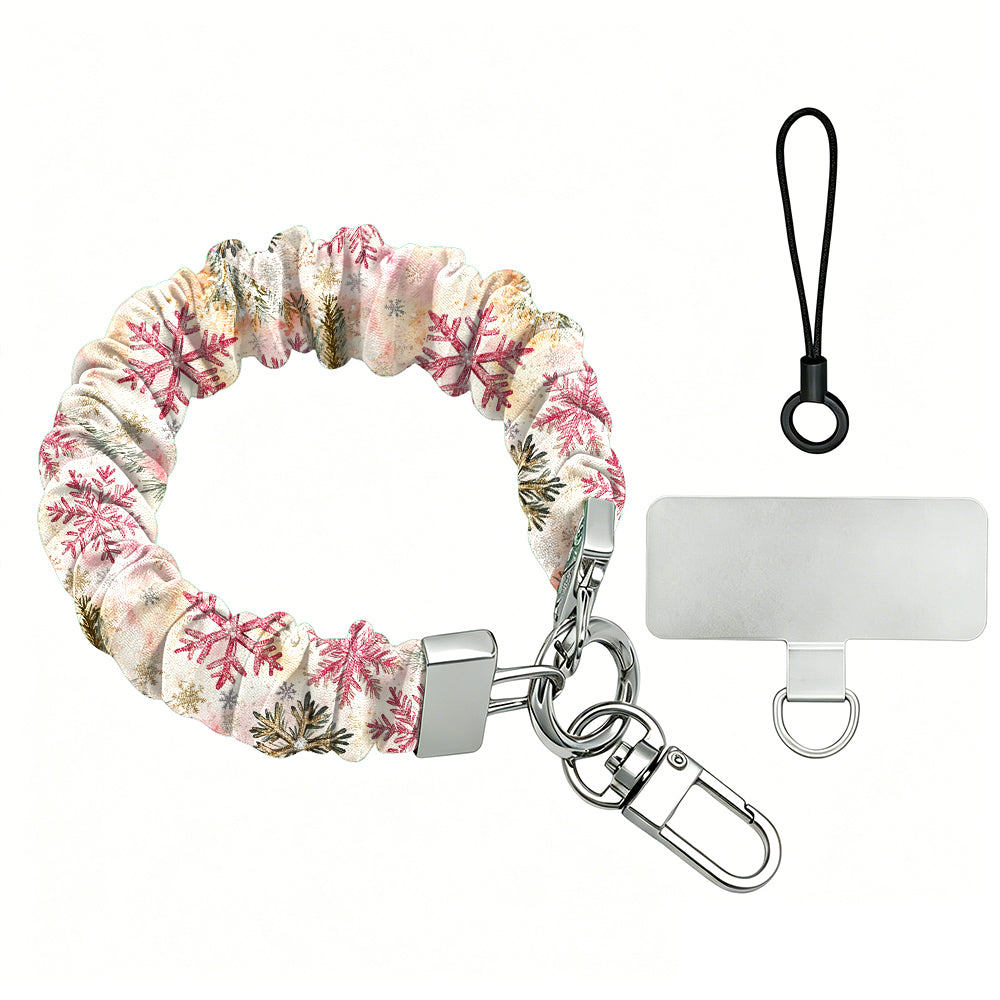 Champagne Snowfall scrunchie phone wrist strap laid flat, pink and gold snowflakes on cream, with silver clasp, lanyard loop and phone tab