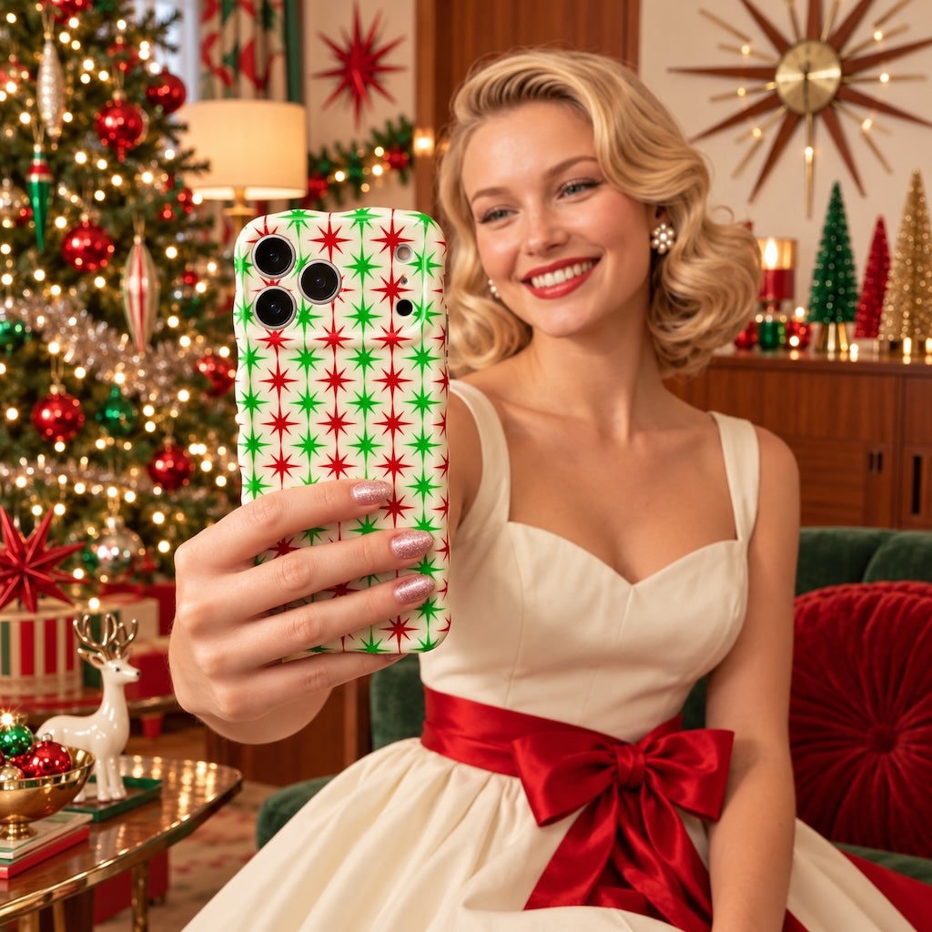 Smiling blonde woman in a cream dress with a red sash taking a selfie with the Tinsel & Stardust iPhone case in a mid-century Christmas living room