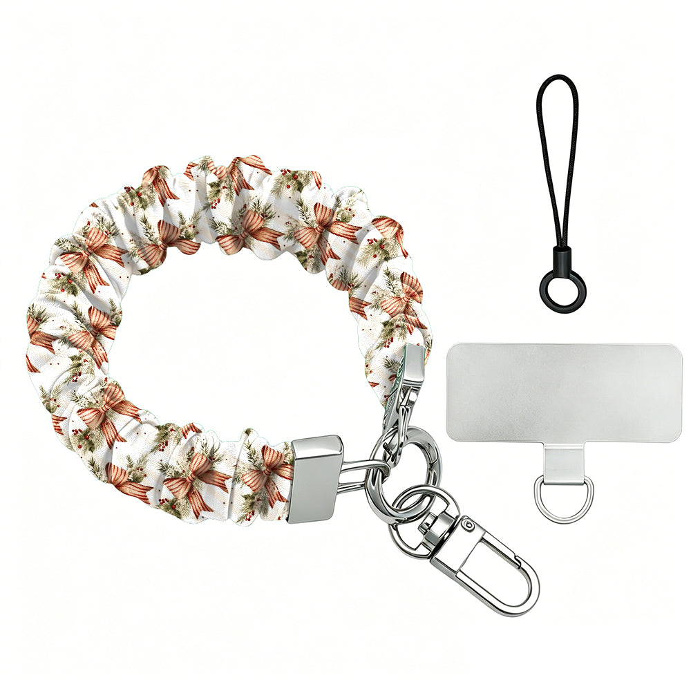 Deck Yourself in Bows & Holly scrunchie phone wrist strap laid flat with silver clasp and phone tab, red ribbon bows and holly on ivory