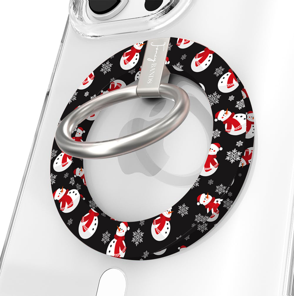 Close-up of the Snowman MagSafe grip ring, black print with white snowmen in red scarves and Santa hats, with brushed silver ring on a clear iPhone case