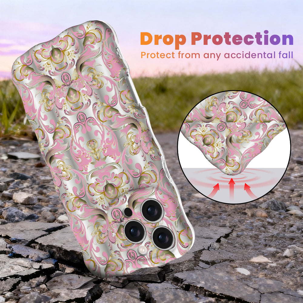 Drop protection graphic for The Pink Heiress Wavy Luxe MagSafe iPhone case, pink and gold baroque scrollwork on pearl white, showing the cushioned wavy edges.