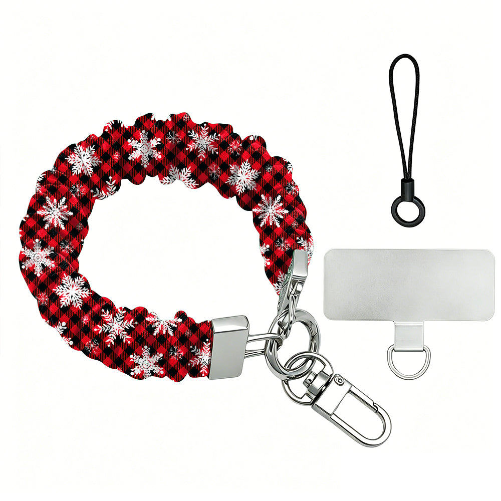 Buffalo Plaid Snowflake scrunchie phone wrist strap laid flat with silver clasp and phone tab, red and black buffalo check with white snowflakes