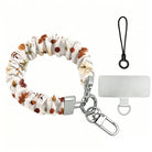 Fall Floral Bliss scrunchie phone wrist strap on a white background, showing the cream fabric with rust and olive autumn florals, silver lobster clasp, black loop cord, and clear attachment tab.