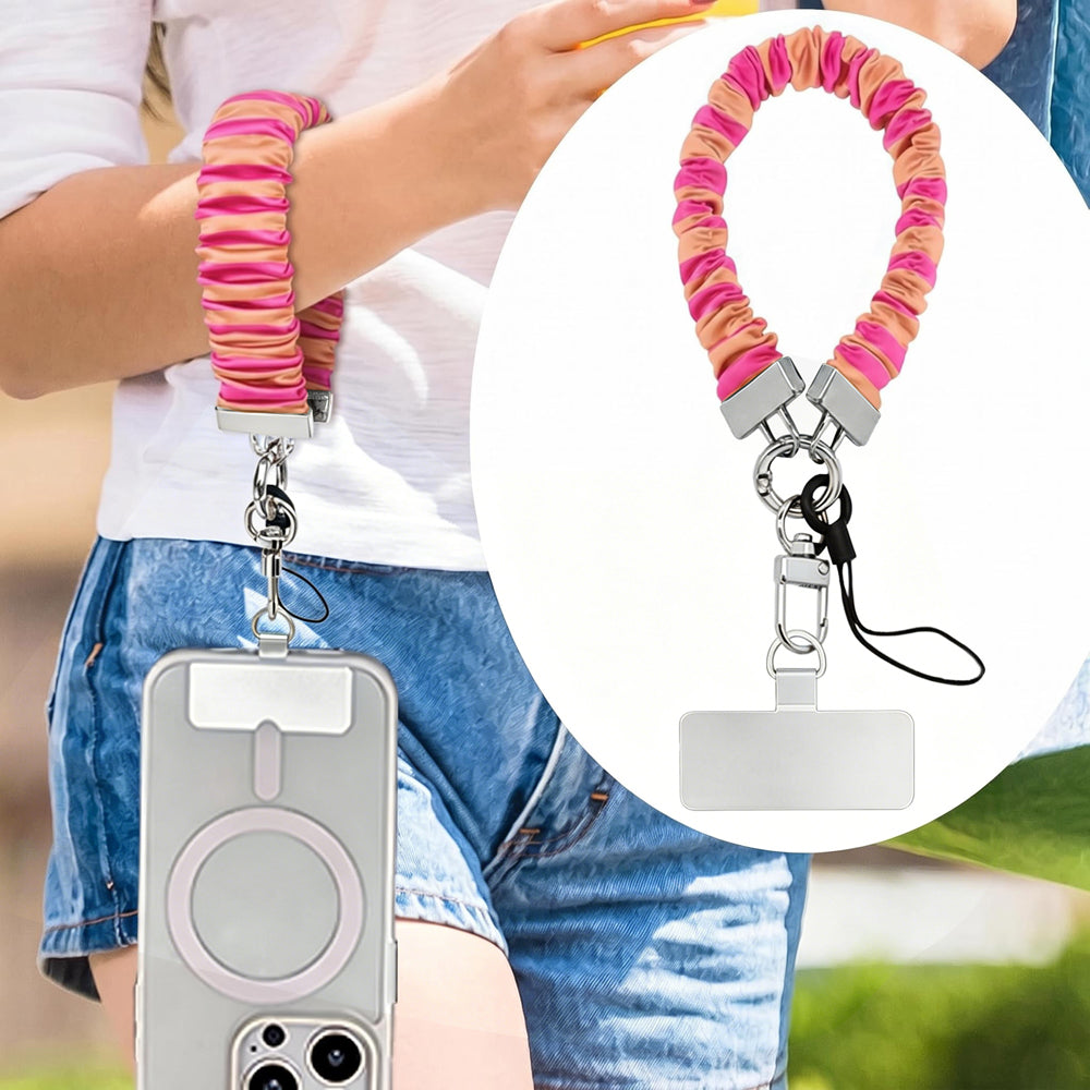Pink and orange striped Candy Citrus Stripes scrunchie phone wrist strap clipped to the matching hot pink and citrus orange striped Wavy Luxe iPhone case, styled on a playful pink and orange heart print background.
