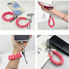 Pink and orange striped Candy Citrus Stripes scrunchie phone wrist strap clipped to the matching hot pink and citrus orange striped Wavy Luxe iPhone case, styled on a playful pink and orange heart print background.