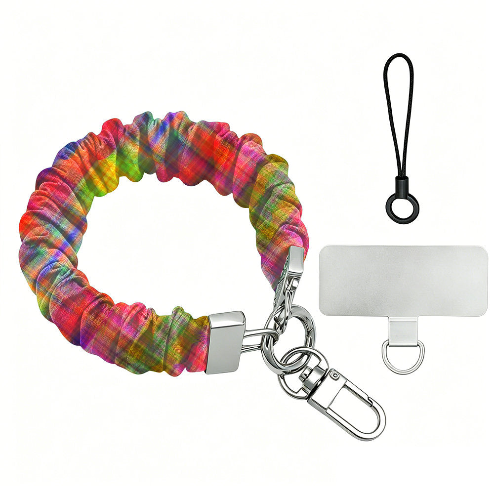 The Hazy Tartan scrunchie phone wrist strap shown on its own in blurred rainbow plaid, with the silver lobster clasp, black loop cord and phone attachment tab.