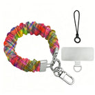 The Hazy Tartan scrunchie phone wrist strap shown on its own in blurred rainbow plaid, with the silver lobster clasp, black loop cord and phone attachment tab.