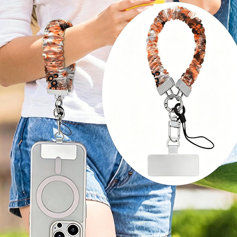 Fall Blooms autumn floral scrunchie phone wrist strap worn on the wrist with a MagSafe iPhone case, orange and cream pressed-flower print from Fancy Bands