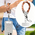 Fall Blooms autumn floral scrunchie phone wrist strap worn on the wrist with a MagSafe iPhone case, orange and cream pressed-flower print from Fancy Bands