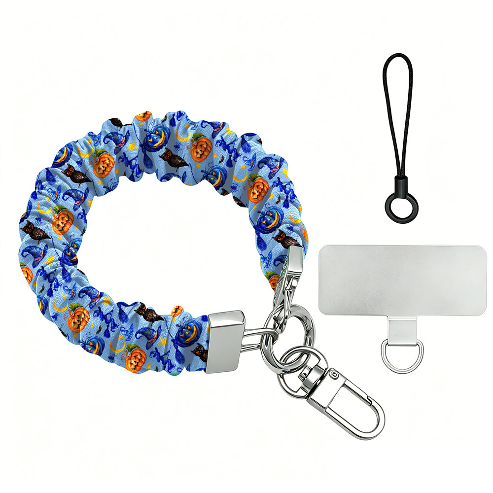 The Bewitching Hour Scrunchie Phone Wrist Strap with metal clasp and phone attachment tab, periwinkle blue with orange pumpkins, witch hats and owls.