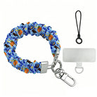 The Bewitching Hour Scrunchie Phone Wrist Strap with metal clasp and phone attachment tab, periwinkle blue with orange pumpkins, witch hats and owls.