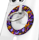 Jack-O-Lantern Jive Hold It Fancy MagSafe grip ring shown on a clear iPhone case, purple ring covered in glowing orange pumpkins and ghosts.