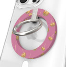 Caramel Coated Cutie Hold It Fancy MagSafe grip ring close-up on a clear iPhone case, showing the rose-pink ring scattered with golden caramel apples and the silver rotating metal ring.