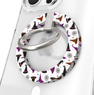 Witch Please Hold It Fancy MagSafe grip ring close-up on a clear iPhone case, showing the white ring scattered with purple, black and striped orange witch hats around the silver rotating ring.