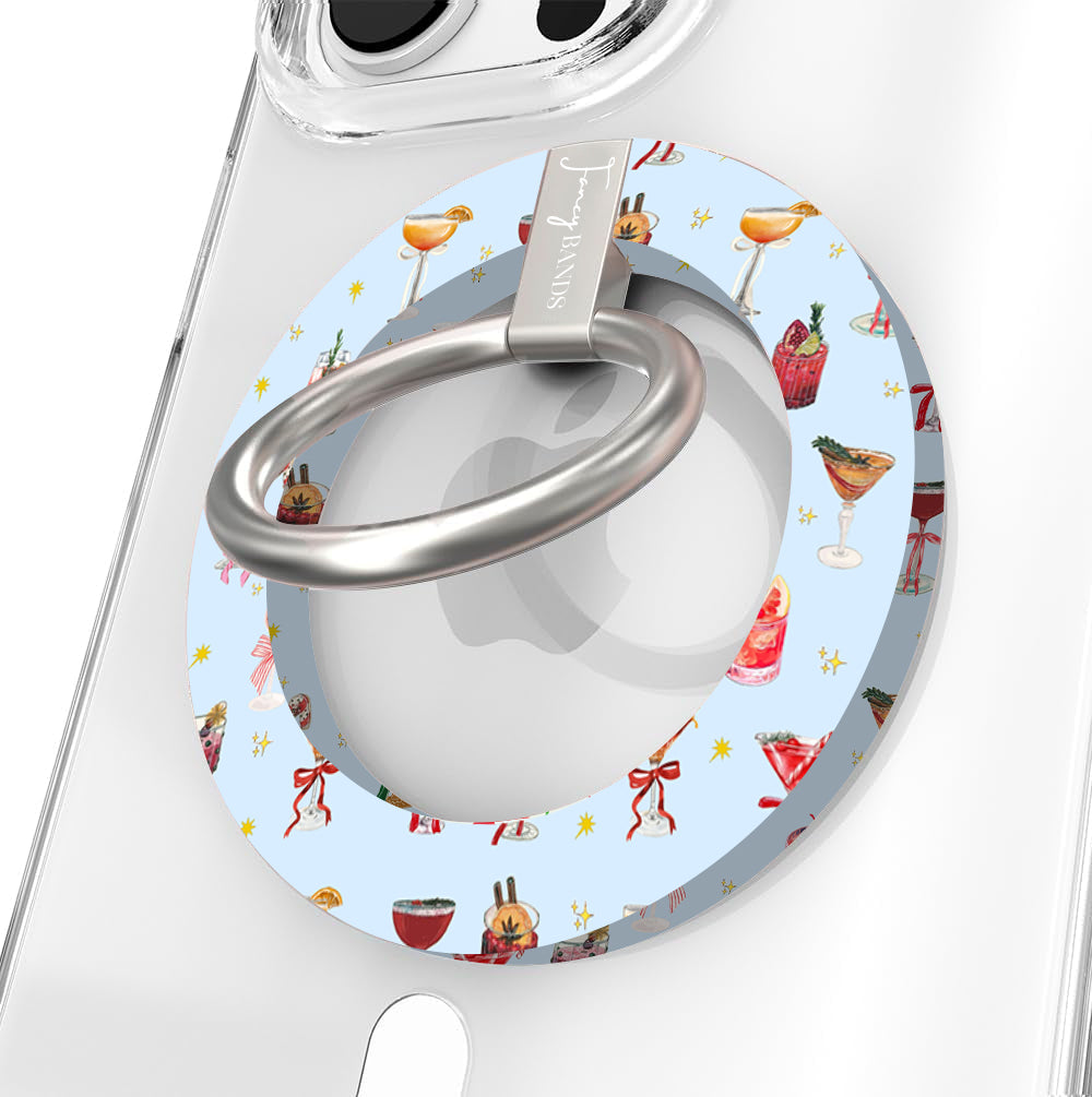 Close-up of the Holiday Spirits, Please? MagSafe grip ring with holiday cocktails and ribbon bows on powder blue and a brushed silver ring on a clear iPhone case