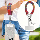 Hazy Tartan scrunchie phone wrist strap worn on the wrist with a phone hanging at the hip, plus a close-up inset of the rainbow plaid strap, clasp and attachment tab.