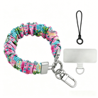 A colorful Seaside State Of Mind scrunchie phone wrist strap in a vintage beach print with Adirondack chairs, surfboard signposts, and palm trees, clipped to the matching Seaside State Of Mind Wavy Luxe iPhone case, styled on a tropical beach background with starfish and shells.