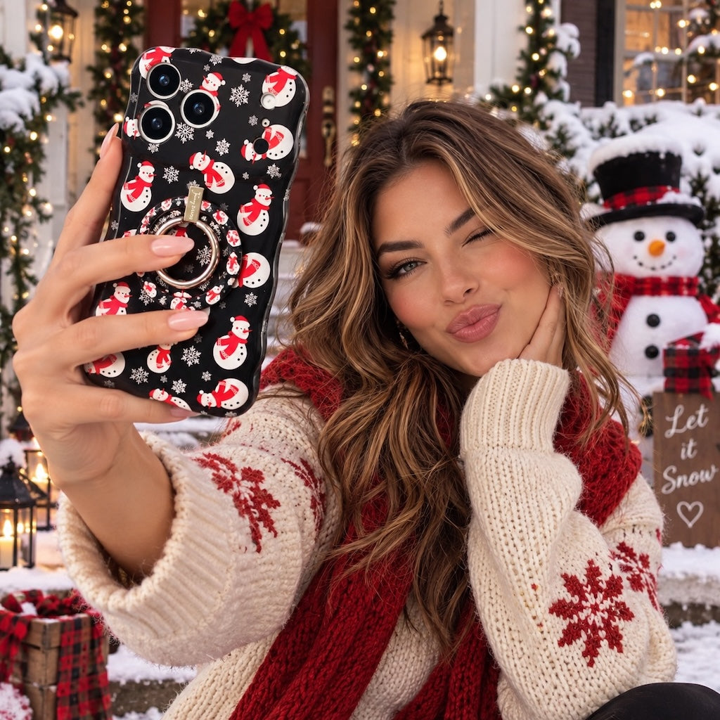 Woman in a snowflake sweater blowing a kiss with her Snowman iPhone case and matching grip ring on a snowy porch