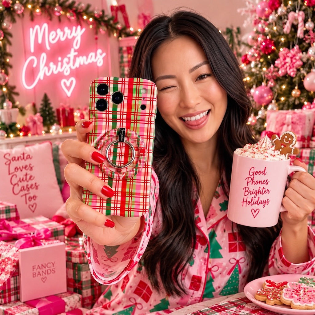 Woman in pink Christmas pajamas winking with her Merry Little Plaid iPhone case and matching grip ring under a Merry Christmas neon sign