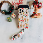 Vintage Christmas iPhone case with its cream scrunchie wrist strap beside a holly wreath, a vintage fawn figurine and a Bright sign