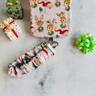 Vintage Christmas scrunchie phone wrist strap clipped below the matching Santa and reindeer iPhone case beside vintage gift boxes