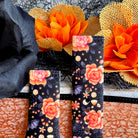Haunted Blossoms Samsung Galaxy Watch band shown as two strap halves standing side by side against orange autumn blooms.