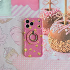 Caramel Coated Cutie MagSafe grip ring attached to the matching Caramel Coated Cutie iPhone case, styled beside caramel apple artwork on a pink fall mood board.