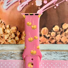 Close-up of the Caramel Coated Cutie Apple Watch band showing the glossy caramel dip detail on each little apple and the buckle end of the pink strap.