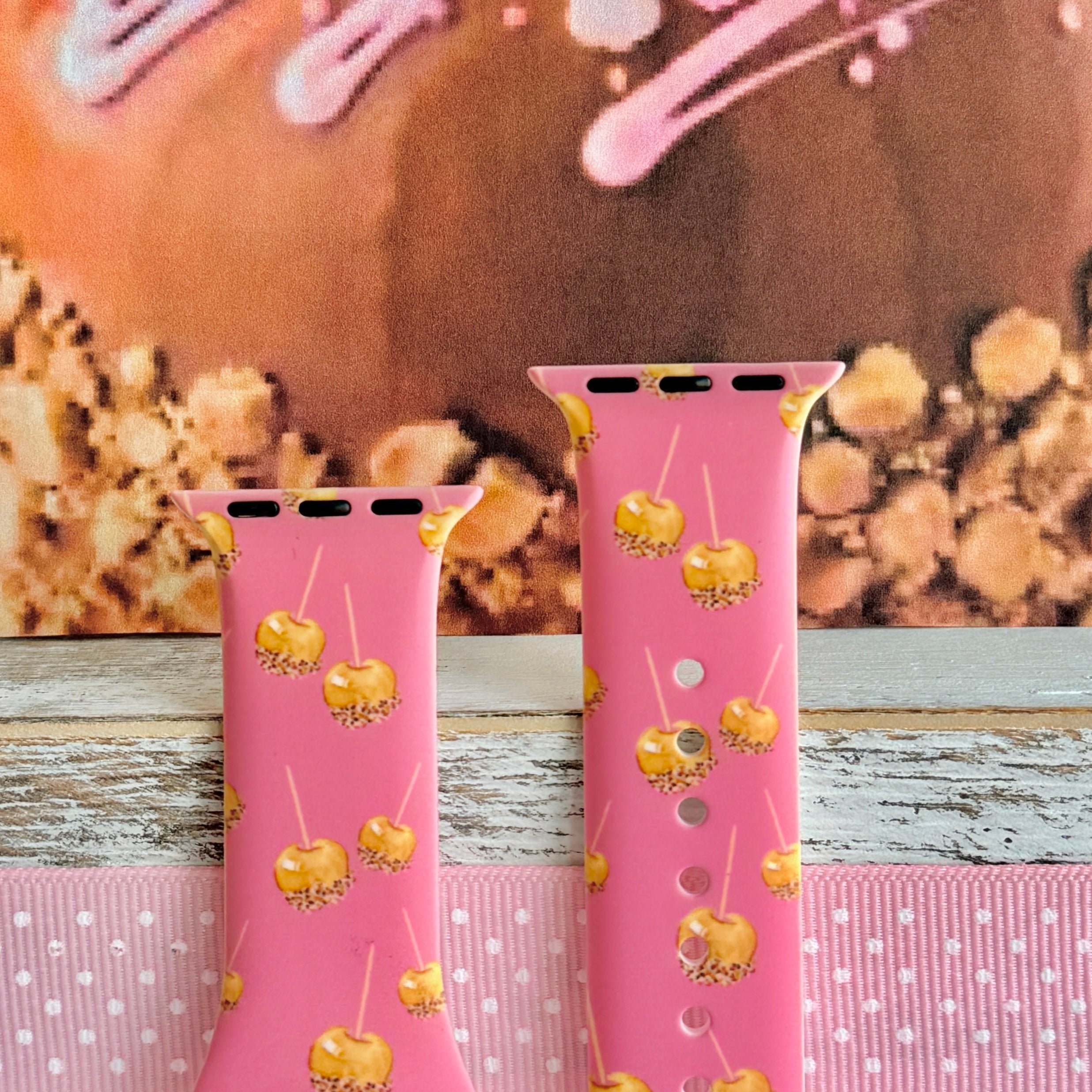 Caramel Coated Cutie Apple Watch band front view of both strap halves against a caramel apple backdrop, showing the pink silicone and the adjustment pin holes.
