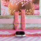 Caramel Coated Cutie silicone Apple Watch band shown with an Apple Watch, both strap halves standing upright to display the rose-pink base and golden caramel apple print.