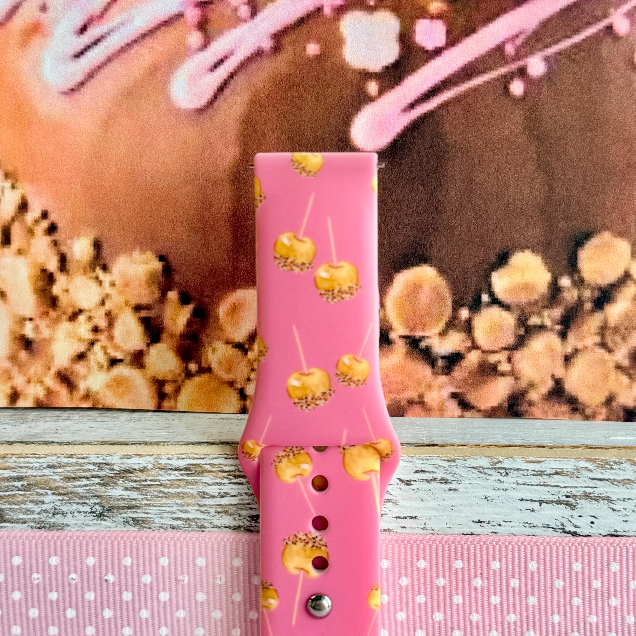 Close-up of the Caramel Coated Cutie Samsung Galaxy Watch band showing the glossy caramel dip detail on each little apple and the buckle end of the pink strap.