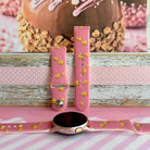 Caramel Coated Cutie silicone Samsung Galaxy Watch band shown with a round Galaxy Watch, both strap halves standing upright to display the rose-pink base and golden caramel apple print.