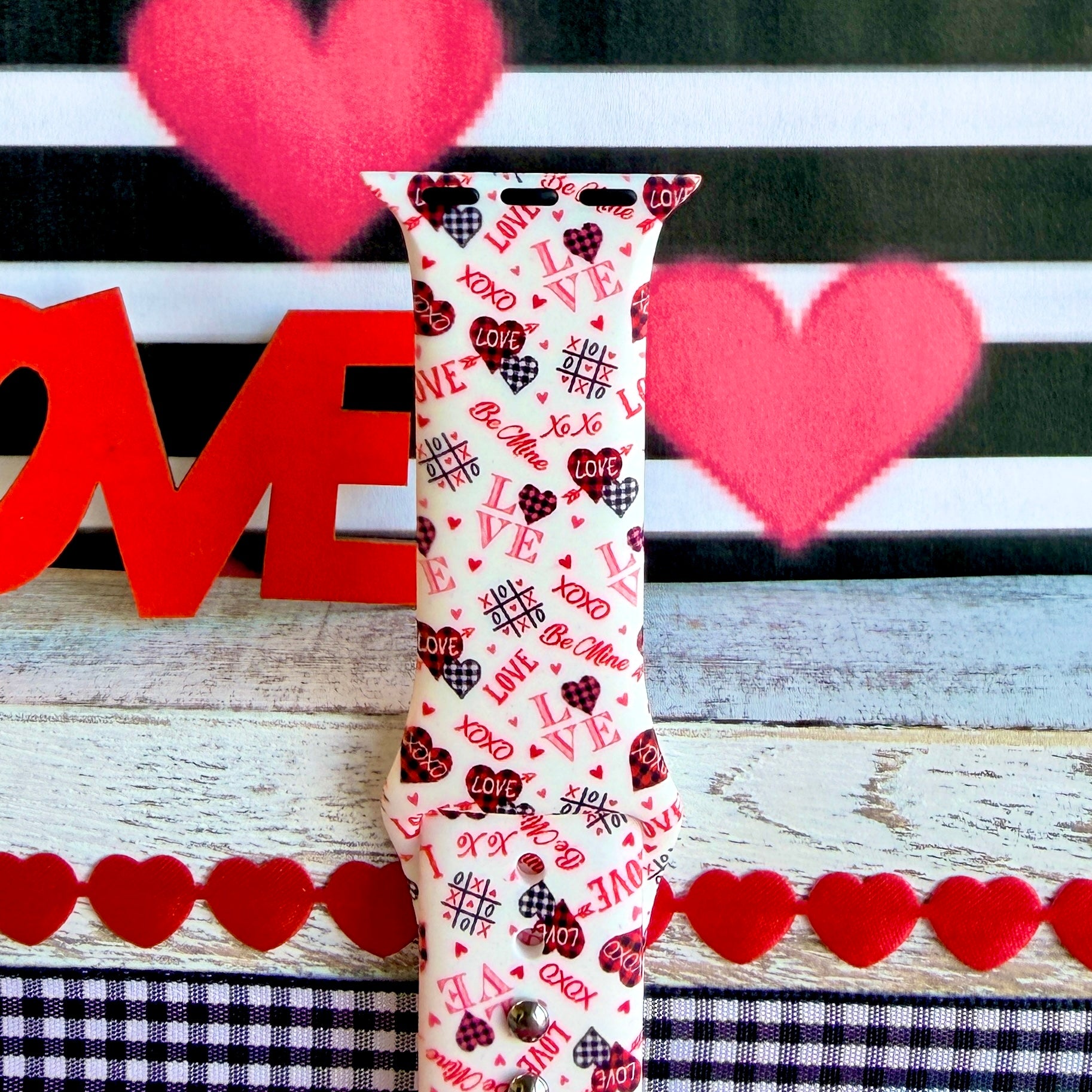 Tick-Tack-Love Apple Watch band with LOVE text, XOXO, and hearts in pink and red on white background with Valentine's decor
