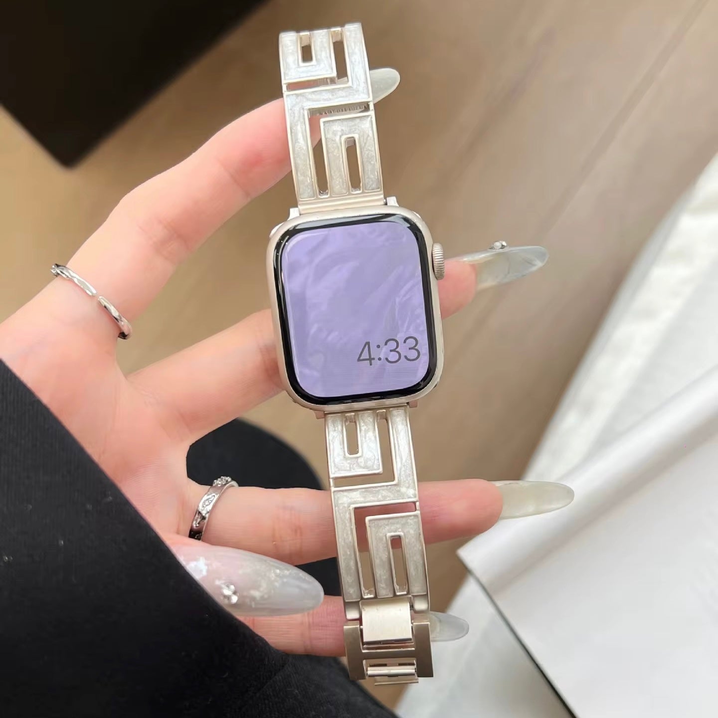 Axiom Link stainless steel Apple Watch band with Greek key cut-out pattern in brushed silver finish on a woman's wrist