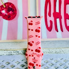 Mon Cheri Apple Watch band with red cherries, hearts, and French text on pink background with CHERI sign
