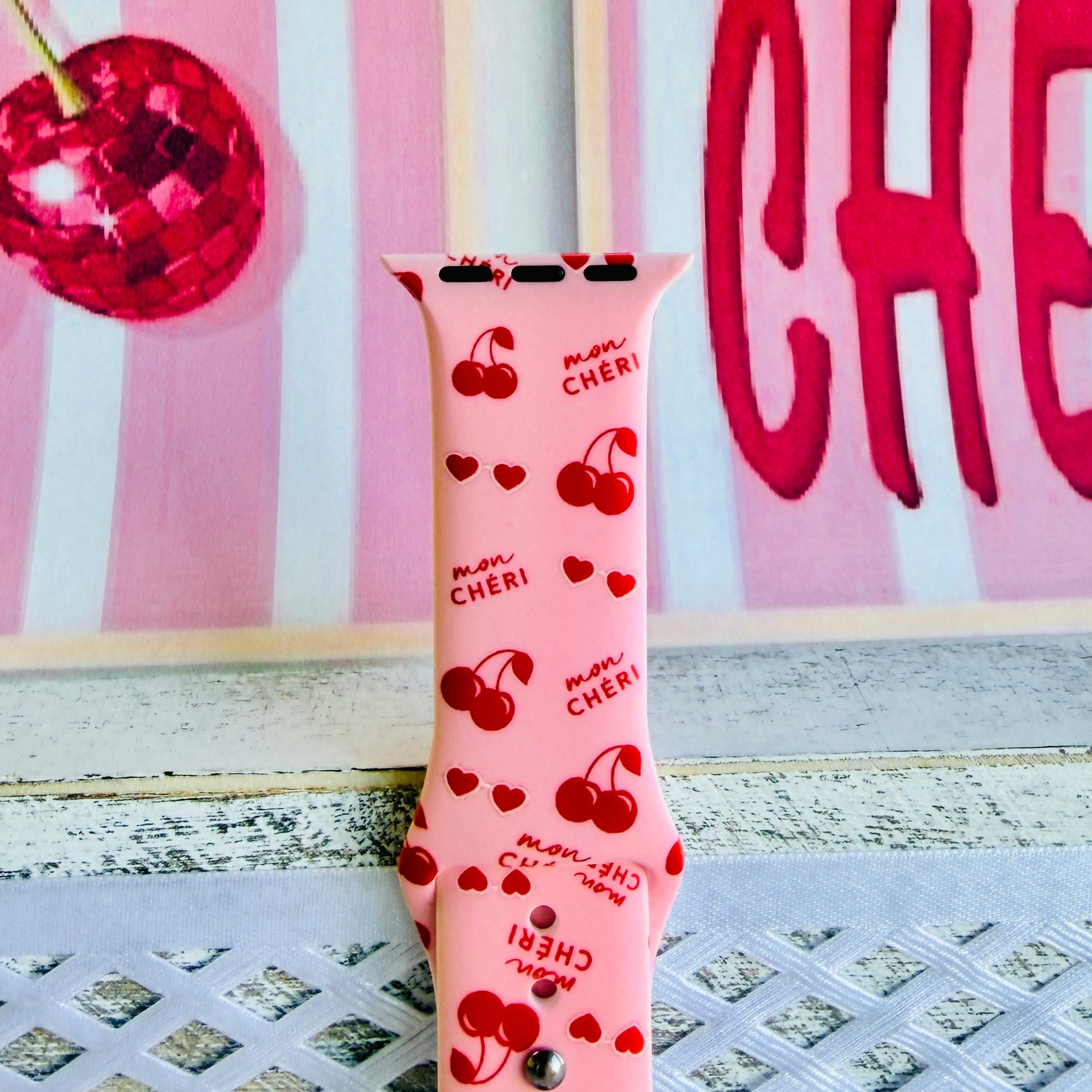 Mon Cheri Apple Watch band with red cherries, hearts, and French text on pink background with CHERI sign
