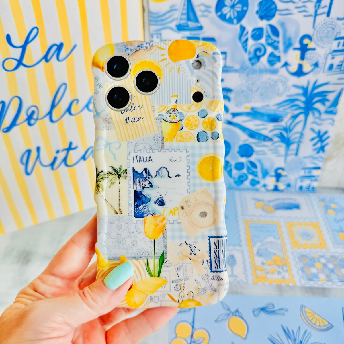 Hand holding the La Dolce Summer Wavy Luxe MagSafe iPhone case, lemons, blue gingham and Italian postcard motifs