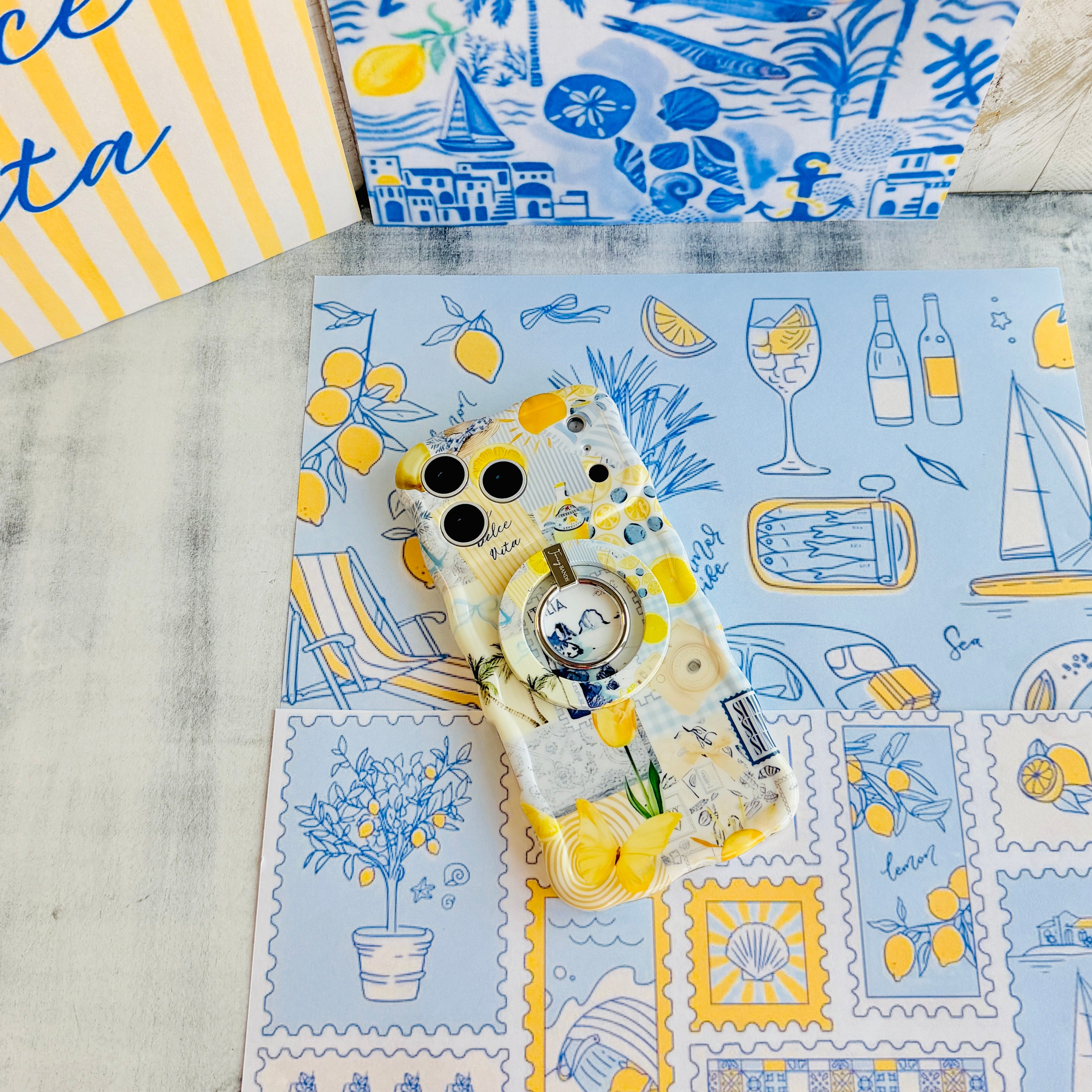 Trendy light yellow and blue wavy iPhone case featuring a Mediterranean collage of lemons, Capri travel stamps, and yellow tulips with a high-gloss finish.